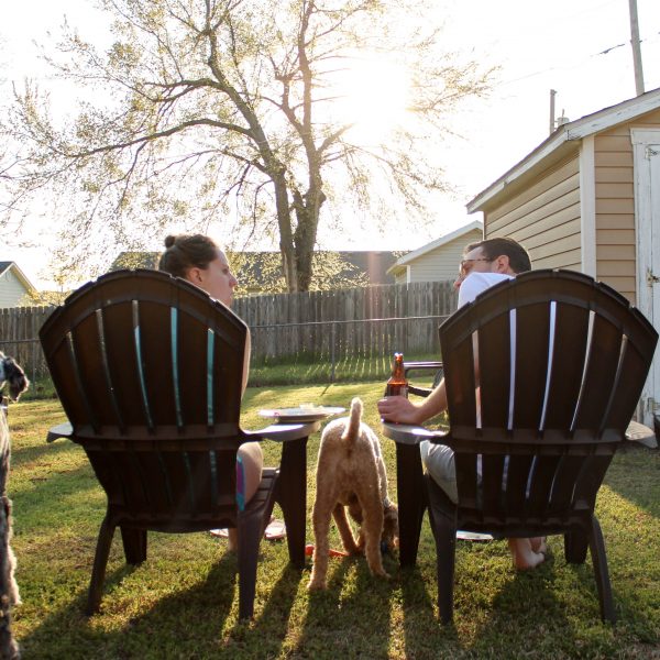 Woman and man sitting in lawn chairs next to two dogs